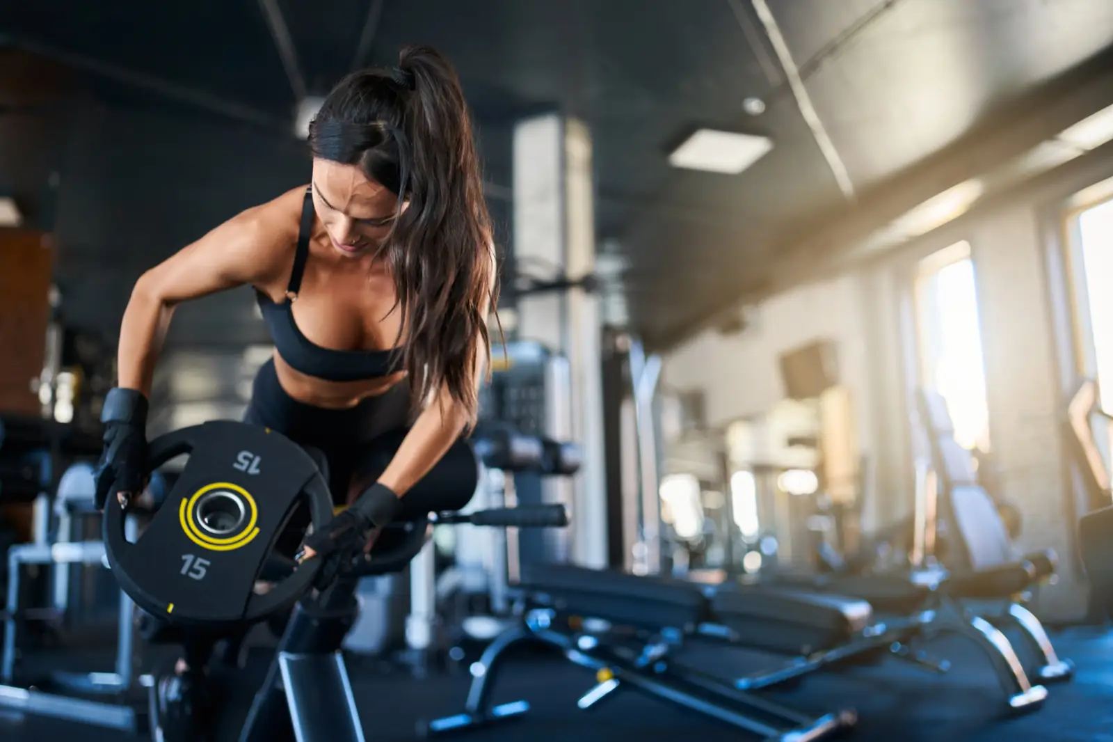 Aluna treinando com anilha de 15 kg no salão